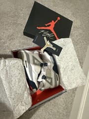 White and navy blue Air Jordan 4 sneakers with gray accents.