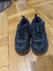 Nike Vomero Kids‘ Shoes in black featuring mesh and synthetic leather paneling.